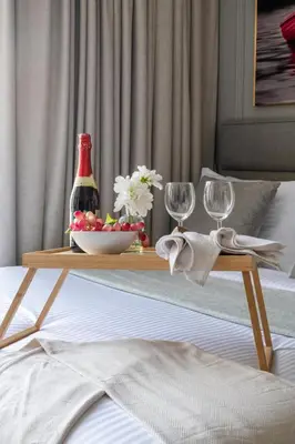 a table with a bottle of wine and glasses on a bed at Frank Porter - Oxford 212 in Dubai