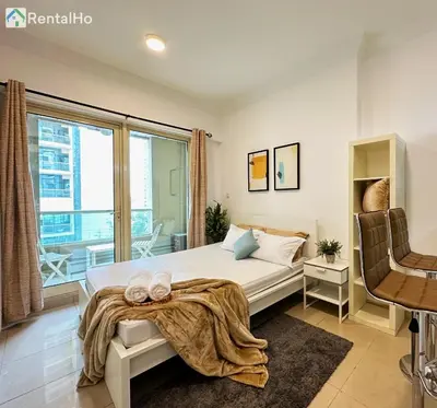 a bedroom with a bed and a large window at Quiet Studio with Balcony and Roof Top Pool in Dubai Marina in Dubai