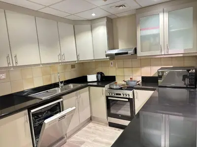 a kitchen with black counter tops and white cabinets at La buena vida holiday homes - Deluxe 3 bedroom apartment on the beach in Dubai