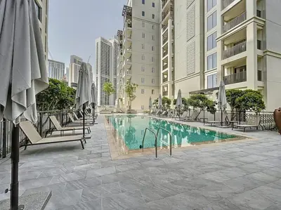 a swimming pool with chairs and umbrellas next to buildings at Sunset at Creek Beach - Exquisite Two Bedroom in Dubai