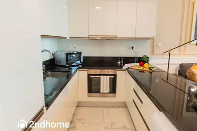 a kitchen with white cabinets and a microwave at 2ndHome - Amna Tower, Al Habtoor City in Dubai