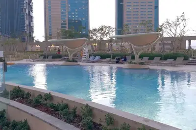 a large swimming pool with chairs and buildings at Downtown 3BR Luxe, Burj & Fountain View Bliss Near Dubai Mall in Dubai