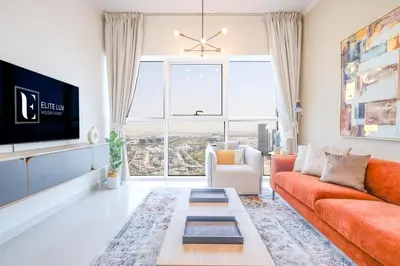 a living room with an orange couch and a tv at Elite LUX Holiday Homes - Serene Golf View Living 1 BHK in Damac Hills, Dubai in Dubai