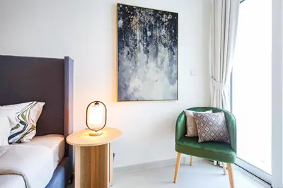 a bedroom with a bed and a green chair at Elite LUX Holiday Homes - Serene Golf View Living 1 BHK in Damac Hills, Dubai in Dubai