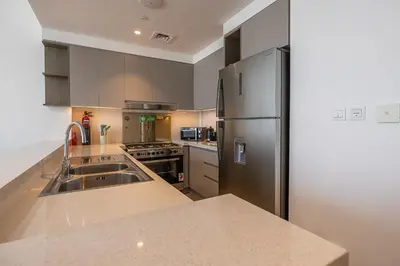 a kitchen with a sink and a refrigerator at Spacious 3BDR with Maid Room I Creek Harbour I Creek Gate Tower 2 in Dubai
