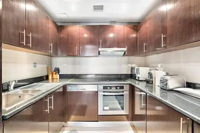 a kitchen with wooden cabinets and stainless steel appliances at StoneTree - Anantara South Residences 2 BR - Palm Jumeirah in Dubai
