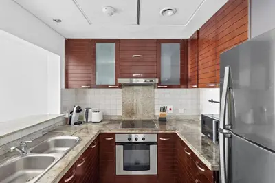 a kitchen with wooden cabinets and a stainless steel appliance at StoneTree - Marina Tower 1BR - Dubai Marina in Dubai
