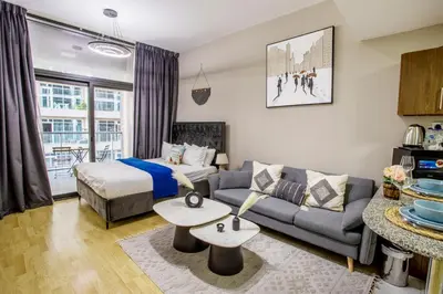a living room with a couch and a bed at Modern Silicon Oasis Studio Near Academic City in Dubai