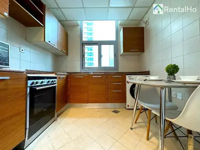 a kitchen with wooden cabinets and a table in it at Big Studio w/ Balcony and easy access to the Beach in Dubai