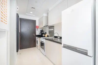 a large kitchen with white cabinets and appliances at Floral Charm studio in Damac Hills by Suiteable in Dubai