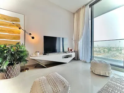 a living room with a tv and a large window at Modern 1 BR Apartment at JVC Dubai Prime Location! in Dubai