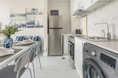 a kitchen with a refrigerator and a table with chairs at Frank Porter - Square Tower in Dubai