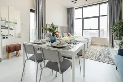 a white dining room with a table and chairs at Frank Porter - Square Tower in Dubai