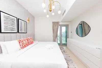 a white bedroom with a bed and a mirror at Charming Brand New 2BR close to the Beach in Dubai