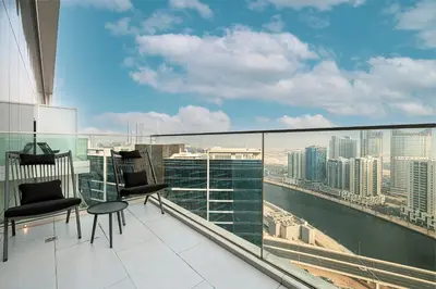 a balcony with chairs and a view of the city at Magnificent 3BR Spectacular Canal & Burj View in Dubai