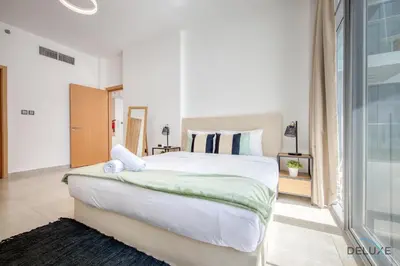a bedroom with a large white bed and a window at Upbeat 1BR at Pantheon Elysee Jumeirah Village Circle by Deluxe Holiday Homes in Dubai