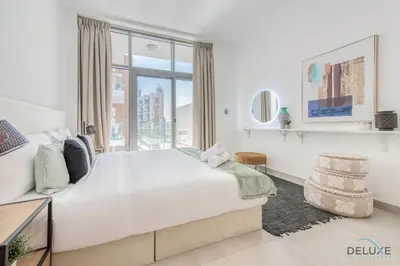 a white bedroom with a large bed and a window at Upbeat 1BR at Pantheon Elysee Jumeirah Village Circle by Deluxe Holiday Homes in Dubai