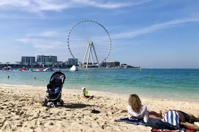 a group of people sitting on a beach with a wheel at Shams Apart on JBR - 1 Bedroom - Marina View in Dubai