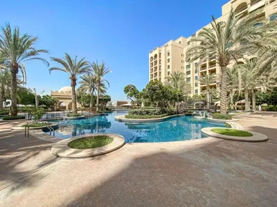 a large swimming pool with palm trees and a building at StoneTree - Fairmont North 2 BR - Beach Access in Dubai