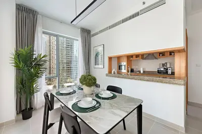 a dining room with a table and chairs and a kitchen at StoneTree - Attessa Tower 1BR - Amazing View in Dubai
