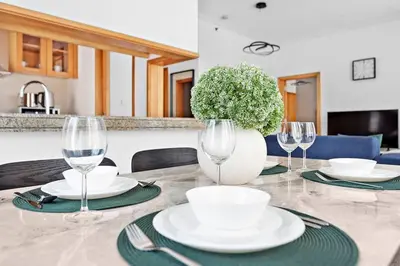 a table with plates and glasses and a vase with a plant at StoneTree - Attessa Tower 1BR - Amazing View in Dubai