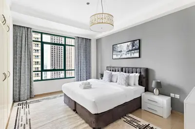 a white bedroom with a large bed and a window at StoneTree - Marina Crown 1 BR - Dubai Marina in Dubai