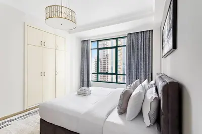 a white bedroom with a large bed with a window at StoneTree - Marina Crown 1 BR - Dubai Marina in Dubai