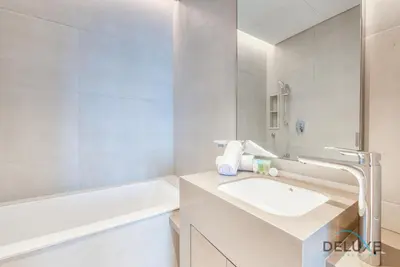 a white bathroom with a sink and a bath tub at Stylish 1BR in Prime Location, Book Your Stay by Deluxe Holiday Homes in Dubai