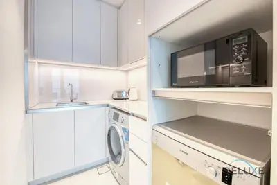 a kitchen with a microwave and a washer and dryer at Stylish 1BR in Prime Location, Book Your Stay by Deluxe Holiday Homes in Dubai