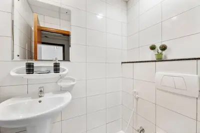 a white bathroom with a sink and a mirror at StoneTree - Marina Pinnacle 1 BR - Partial Marina View in Dubai