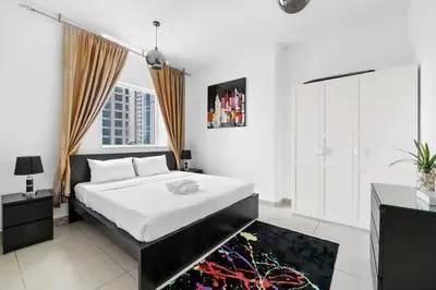 a white bedroom with a bed and a window at StoneTree - Marina Pinnacle 1 BR - Partial Marina View in Dubai