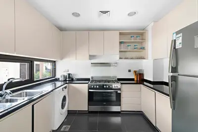 a white kitchen with a stove and a sink at StoneTree - Pelham Villa 3 BR - Damac Hills in Dubai