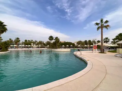 a pool at a resort with palm trees and umbrellas at StoneTree - Pelham Villa 3 BR - Damac Hills in Dubai