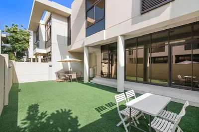 a patio with a table and chairs on a lawn at StoneTree - Pelham Villa 3 BR - Damac Hills in Dubai