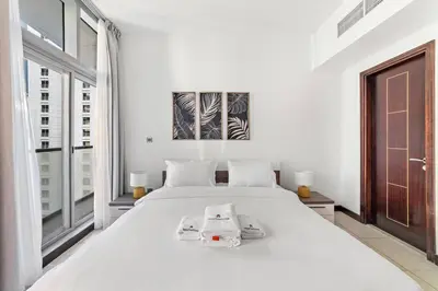a white bedroom with a large white bed and a window at StoneTree - Indigo Tower 1BR - Panoramic View in Dubai