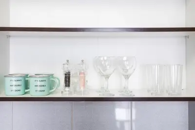 a shelf with wine glasses and mugs on it at Stylish Sports City Studio Golf View PoolGym in Dubai