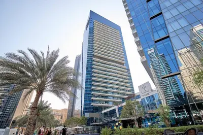 a tall building with a palm tree in a city at StoneTree - Modern 1BR near Dubai Marina Mall in Dubai