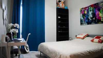a bedroom with a bed and a desk and blue curtains at VIDA Premier Deluxe - Creek Beach - Beachfront Bliss in Dubai