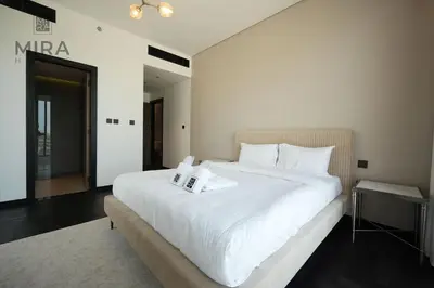 a bedroom with a large white bed with towels on it at Mira Holiday Homes - Newly 1 bedroom with pool access in Dubai