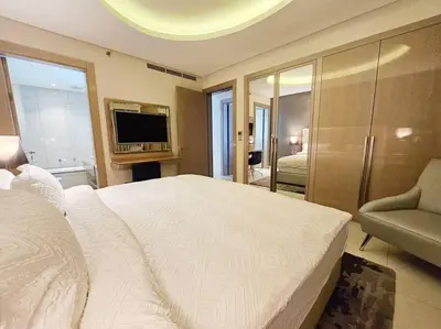 a bedroom with a large white bed and a television at Luxury Paramount Hotel Apt D111 in Dubai