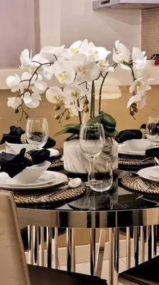 a dining room table with white flowers in a vase at Luxury Paramount Hotel Apt A662 in Dubai