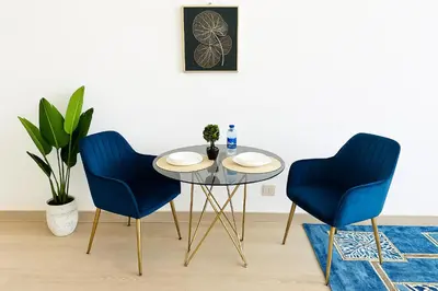 two blue chairs and a table in a room at Luxurious & Modern Studio in JVC in Dubai