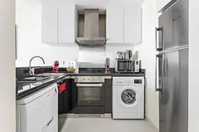 a white kitchen with a dishwasher and a washer at StoneTree - Damac Heights 1BR apartment in Dubai