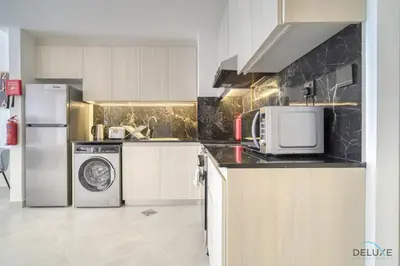 a kitchen with a refrigerator and a washer and dryer at Soothing 1BR at Binghatti Avenue Al Jaddaf by Deluxe Holiday Homes in Dubai