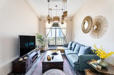 a living room with a blue couch and a tv at ALiving Elegant & Cozy 1BR I Mazaya 11, Liwan in Dubai