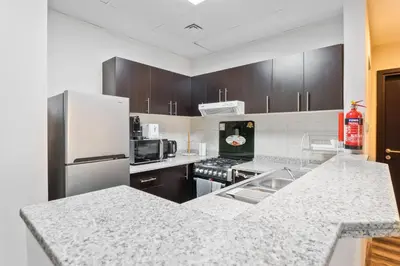 a kitchen with stainless steel appliances and wooden cabinets at ALiving Elegant & Cozy 1BR I Mazaya 11, Liwan in Dubai