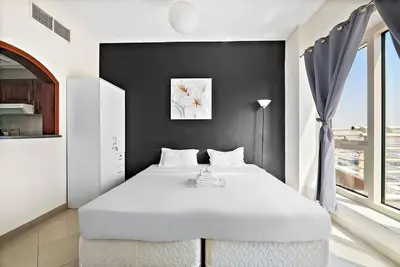 a bedroom with a white bed and a black wall at StoneTree - Cozy Fully-Furnished Studio in JLT in Dubai