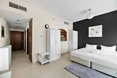 a bedroom with a white bed and a black wall at StoneTree - Cozy Fully-Furnished Studio in JLT in Dubai