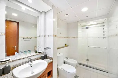 a bathroom with a sink and a toilet and a shower at StoneTree - 1BR apartment with Lake View in Dubai