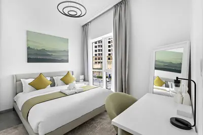 a white bedroom with a large bed and a window at StoneTree - Stylish Apartment with amazing building facilities in Dubai